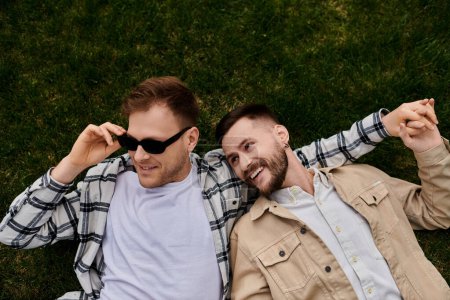 Zwei verliebte Männer, die auf einer grünen Wiese liegen und Gesellschaft voneinander genießen.