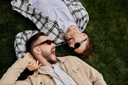 Photo for Two men laying on lush green field. - Royalty Free Image