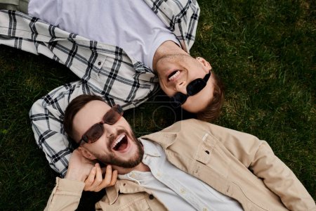 Two loving men laying on the grass in a tender embrace, enjoying the outdoors.