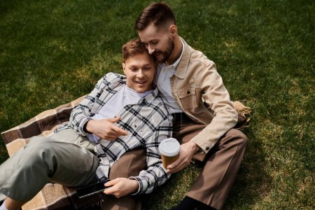 Un couple d'hommes se détendre sur une couverture à l'extérieur, profiter d'un moment serein ensemble.