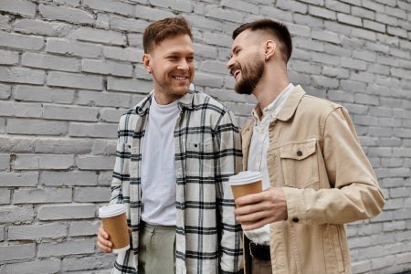 Deux hommes en tenue décontractée debout ensemble, tenant des tasses de café.