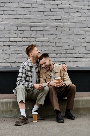 Photo for Two men happily sitting together outdoors. - Royalty Free Image