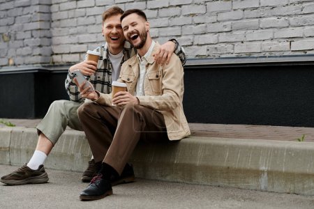 Deux hommes en tenue décontractée assis sur les marches, l'un tenant une bière.