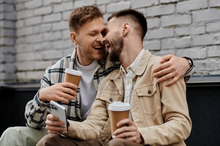Two men in chic outfits enjoy coffee together outdoors.