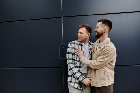 Zwei Männer in lässiger Kleidung stehen dicht beieinander, strahlen Glück und Verbundenheit aus.