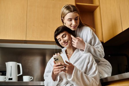 lesbian couple, both in bathrobes, sit together in a hotel room.