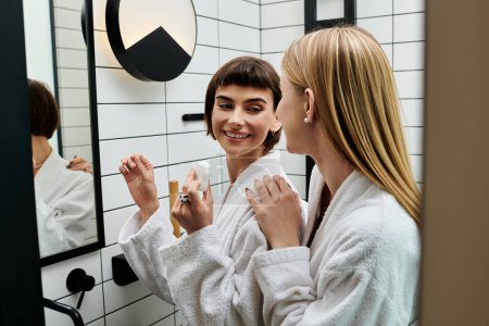 A young woman in a bath robe stands before a mirror, methodically flossing her teeth in a hotel bathroom.