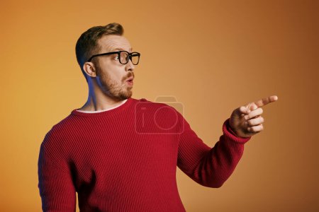Stylish man in red sweater energetically pointing.