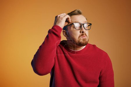 A stylish man in a red sweater and glasses strikes a confident pose.