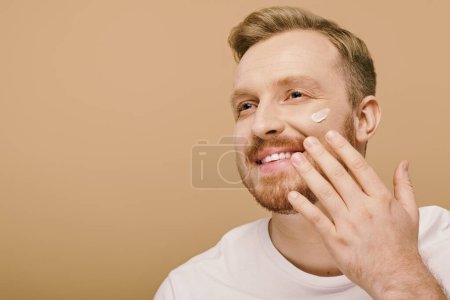 Handsome man in casual attire with a patch of cream on his face.