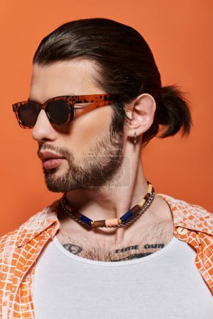 A bearded man in sunglasses and a necklace exudes confidence and style.