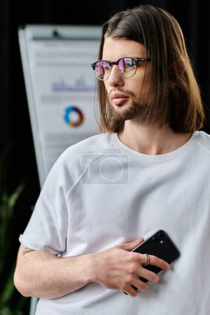 Un hombre de negocios de pelo largo y gafas sosteniendo un teléfono celular.