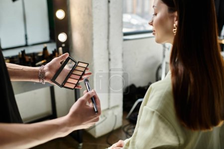 Un maquillador mejora las características de una cliente femenina con una aplicación hábil.