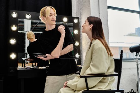 A woman being styled by a makeup artist in front of a mirror.