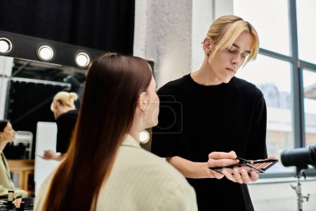 Young woman getting makeup done by professional artist in front of mirror.