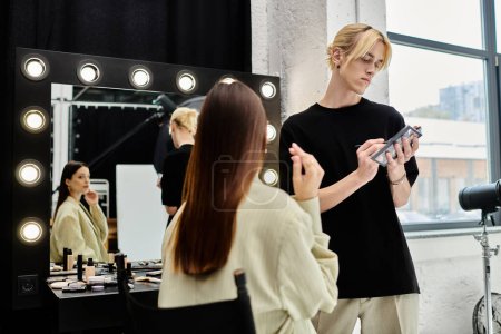 Long haired woman getting makeup done by professional artist in front of mirror.
