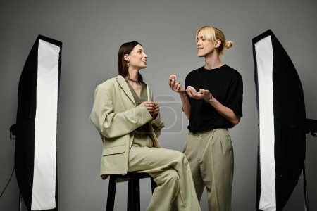 A makeup artist applies makeup to a female client in a photo studio.
