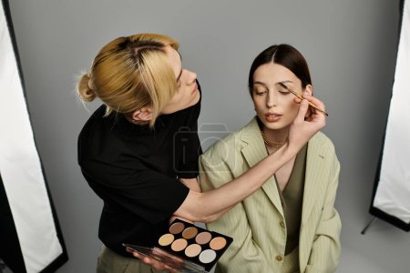 A makeup artist applies makeup on a womans face.