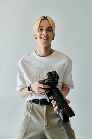 Foto de Young man smiles while holding camera. - Imagen libre de derechos
