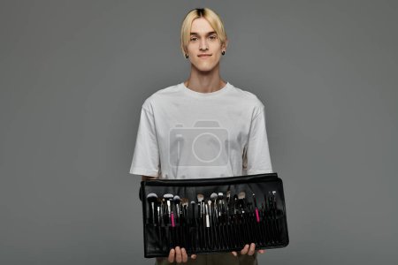 Stylish young man holding a black case full of makeup brushes.