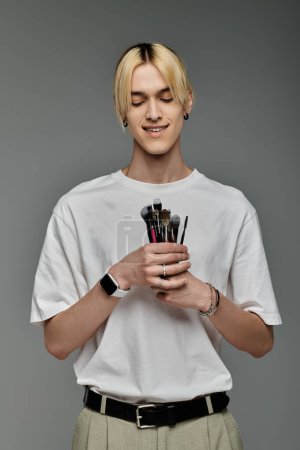 Young man showcasing makeup brushes with style.