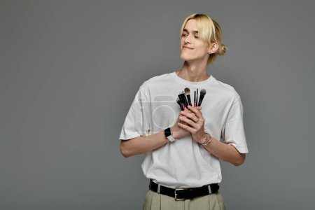 A man skillfully holds a variety of brushes in his hands.