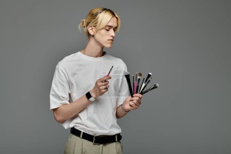 Man gracefully holds a bunch of brushes in her hands.