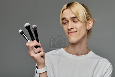 Man gracefully holds a bunch of makeup brushes.