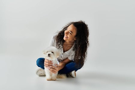 Una joven tiernamente sosteniendo un perro bichon frise en casa.