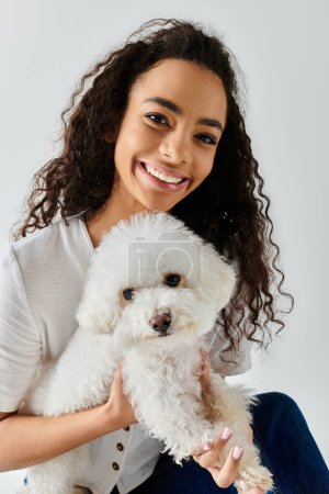 A young woman gently holding a white dog in her arms at home.