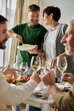 A gay couple enjoys a meal with their family at home.