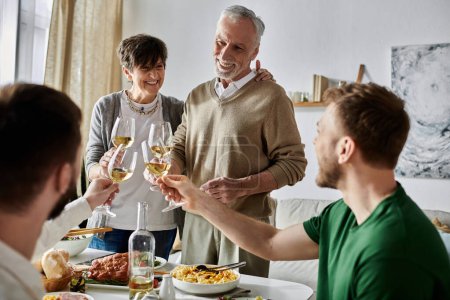 A gay couple toasts with parents during a family gathering.
