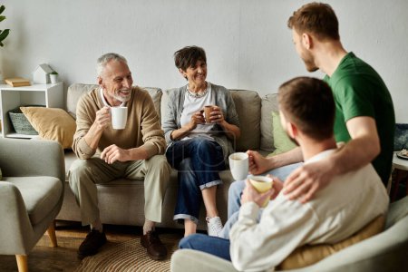 A gay couple enjoys a relaxed afternoon with parents, sharing conversation and beverages.