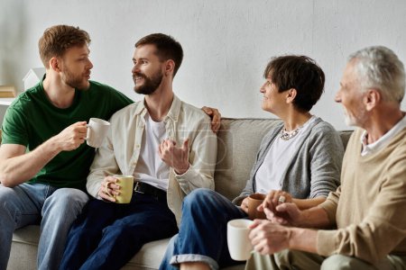 A gay couple and parents share a cup of coffee together at home.