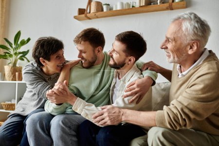 A gay couple sits on a couch with parents, laughing and embracing.