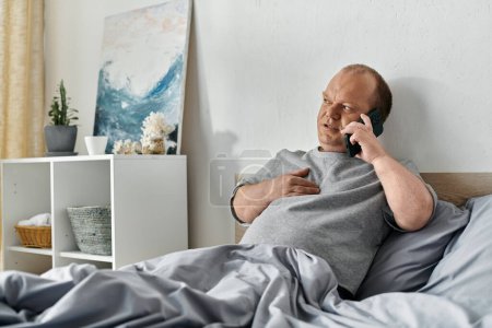 A man with inclusivity sits in bed talking on the phone.