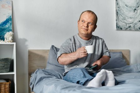 A man with inclusivity sits in bed, enjoying a cup of coffee and his morning routine.