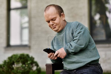 Un hombre con inclusividad se sienta en un banco y usa su teléfono inteligente mientras sonríe.
