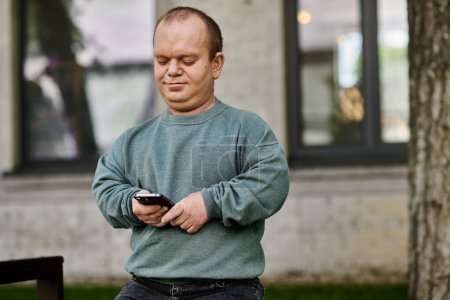 A man with inclusivity in a green sweater checks his phone while walking in a city setting.
