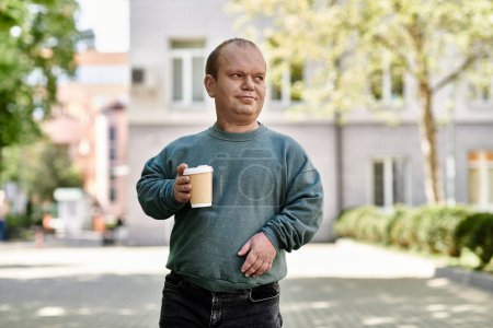 Un homme inclusif marche dans la rue, tenant une tasse de café.