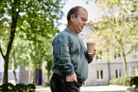 Un homme inclusif, tenant une tasse de café, marche dans une rue de la ville.
