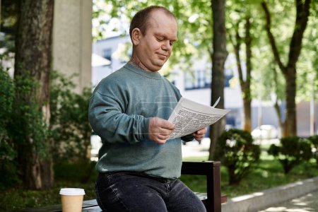 Un hombre con inclusividad se sienta en un banco del parque, lee un periódico y disfruta de una taza de café.