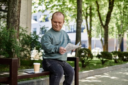 Ein inklusiver Mann sitzt auf einer Parkbank, liest ein Dokument und genießt eine Tasse Kaffee.