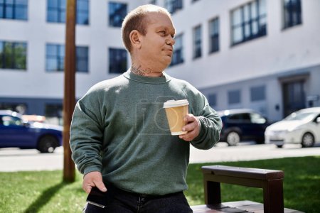 Un homme avec inclusivité marche avec une tasse de café à la main, profitant du paysage urbain autour de lui.