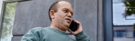 Un homme inclusif parle au téléphone devant chez lui.