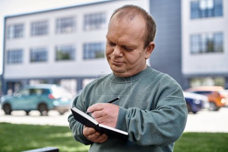 Un hombre con inclusividad está escribiendo en un cuaderno fuera de un edificio.