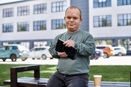 Un hombre con inclusividad se sienta en un banco fuera de un edificio, sosteniendo un cuaderno y un bolígrafo. Parece relajado y contento, tomando notas en su día.