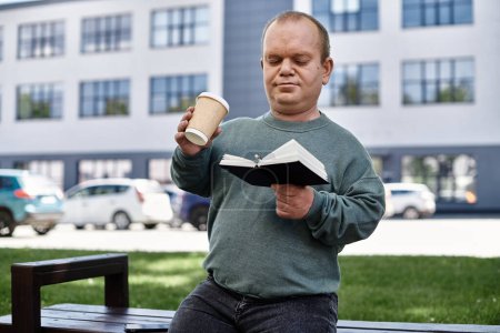 A man with inclusivity enjoying a coffee break while reading a book outside in an urban setting.