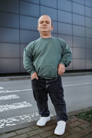 Un homme inclusif se tient sur le trottoir d'une ville, confiant et prêt à embrasser sa journée.