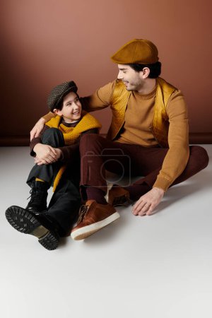 A father and son share a warm moment together, sitting on a white floor.